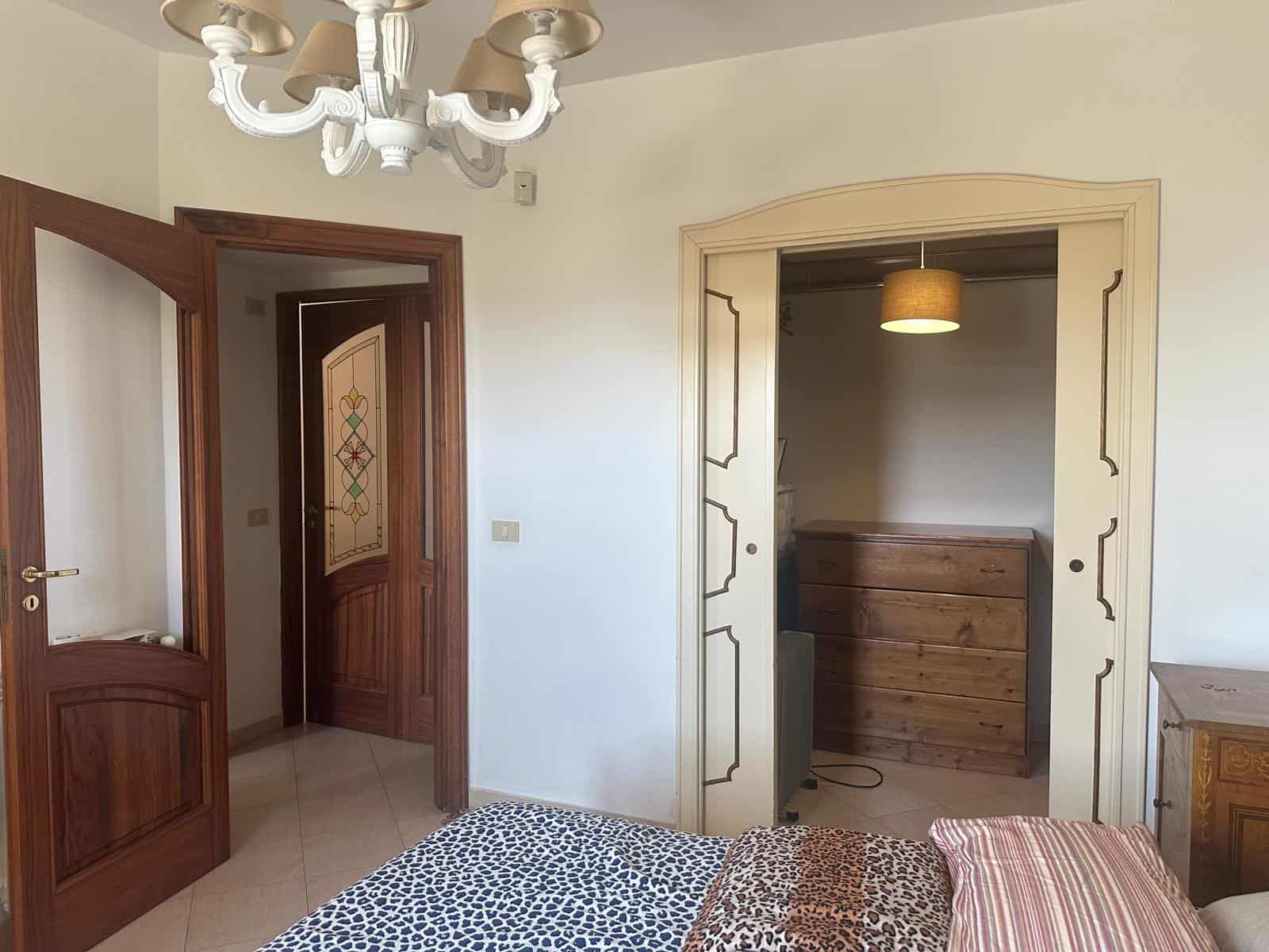 Interno di un appartamento in vendita a Milazzo, con camera da letto, armadio a muro e porta in legno.