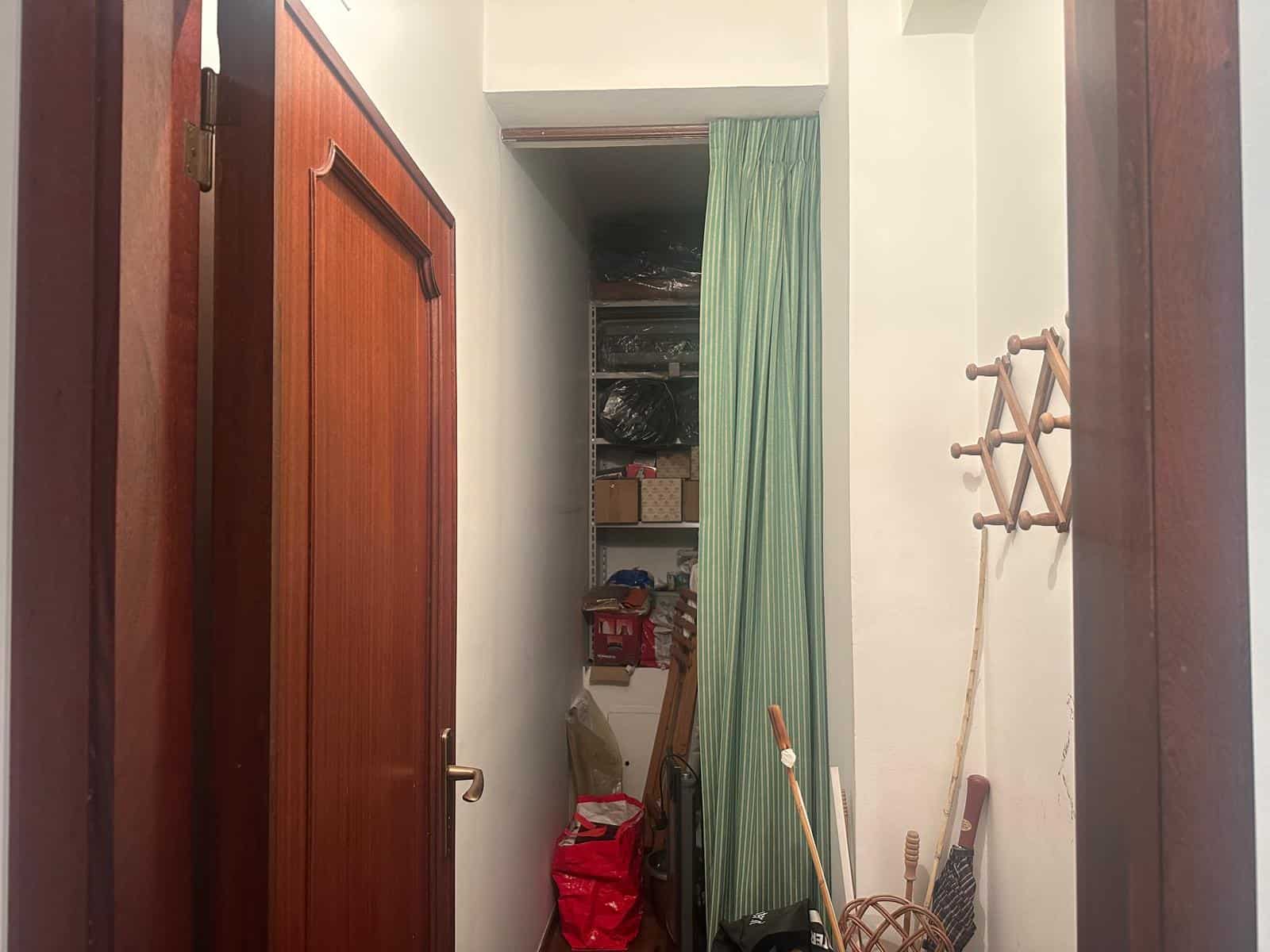 Spazio di stoccaggio in un armadio con scaffali e oggetti vari, vista dall'ingresso di una stanza.