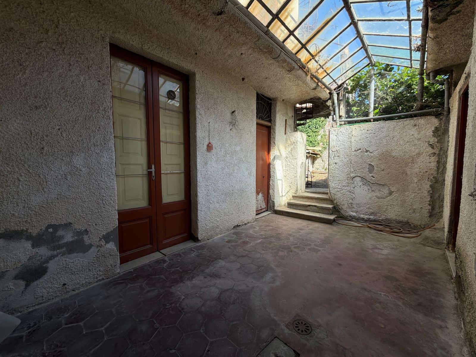 Spazio esterno di una casa indipendente in vendita a Barcellona P.G., con pareti in cemento e tetto in vetro.