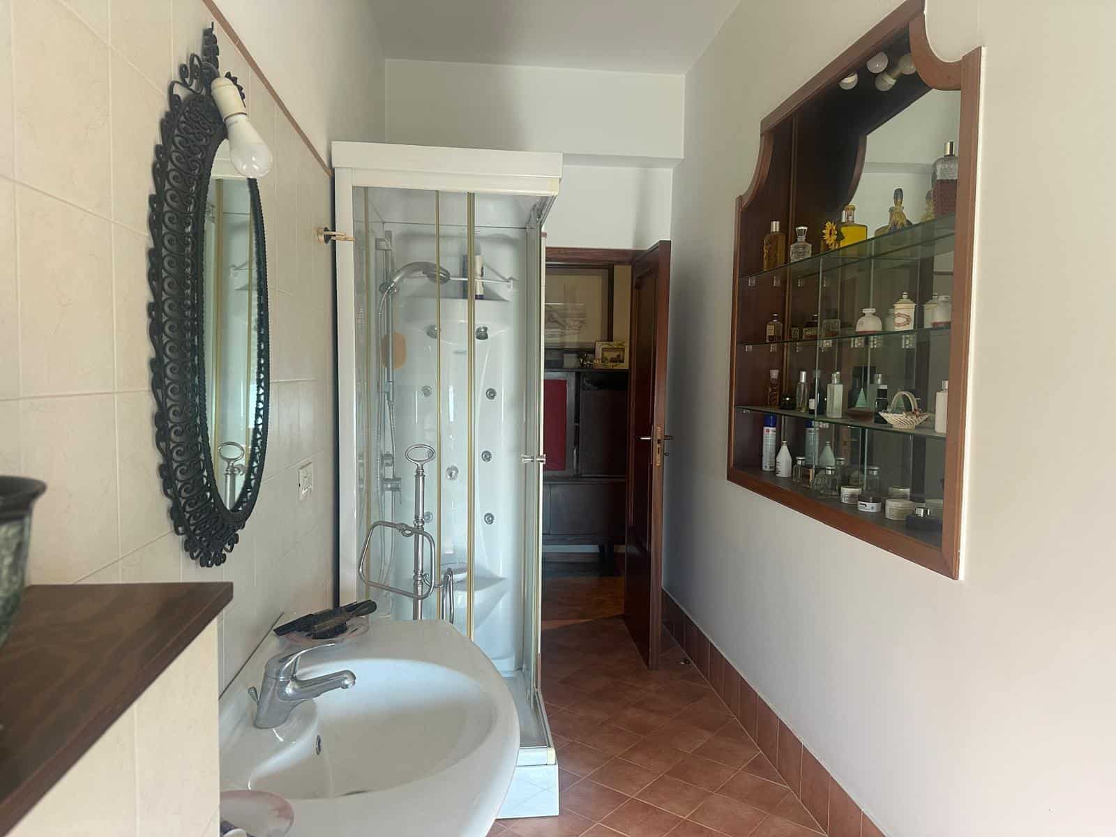 Un bagno con doccia, lavabo e armadietto a muro con prodotti per la cura personale, in un ambiente domestico ben arredato e luminoso, ideale per case in vendita o in affitto.