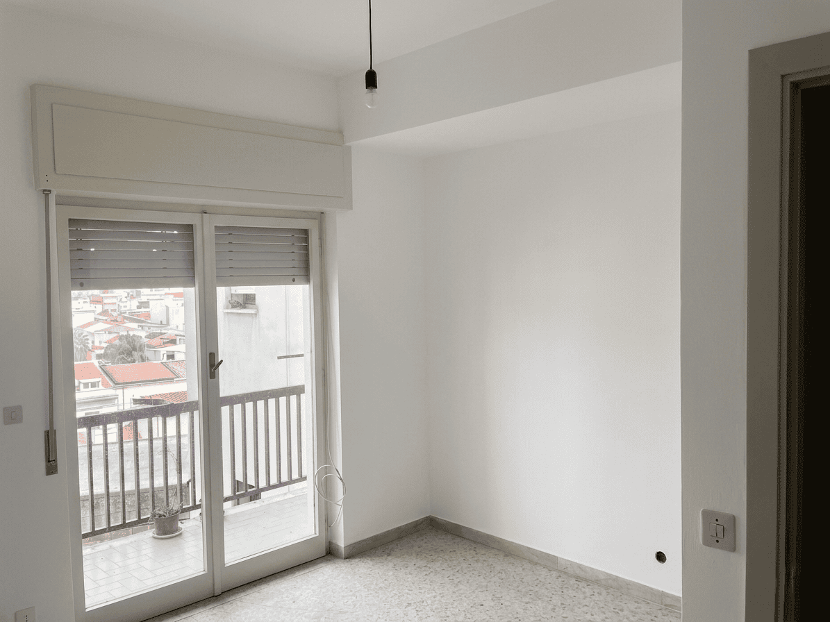 Spazioso soggiorno con porta finestra che apre su balcone, illuminato dalla luce naturale, con vista panoramica sulla città, ideale per ambienti di relax e convivialità.
