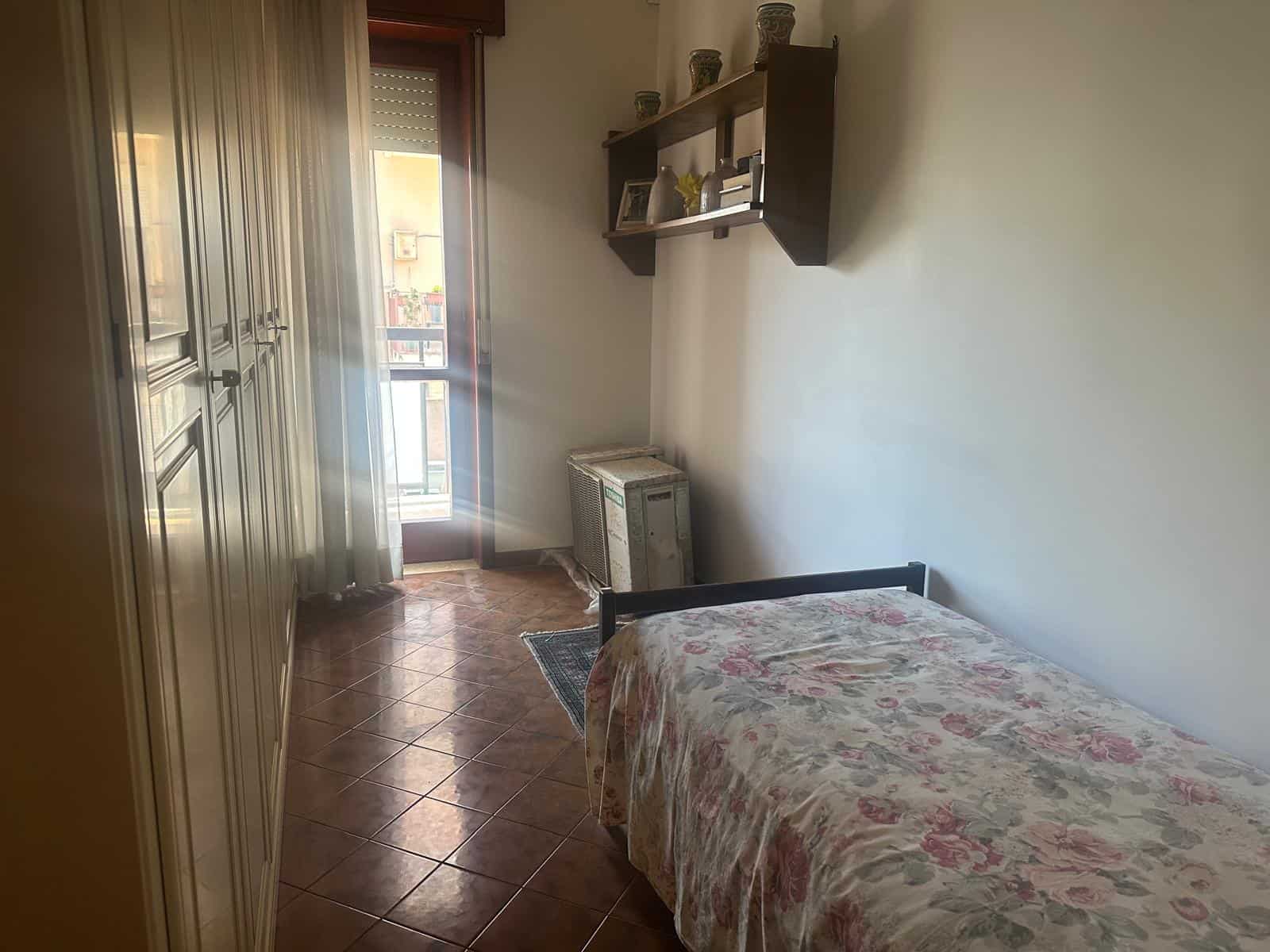 Camera da letto con armadio, letto singolo e balcone, ambiente luminoso e accogliente, arredamento semplice, ideale per soggiorni di breve o lungo termine.