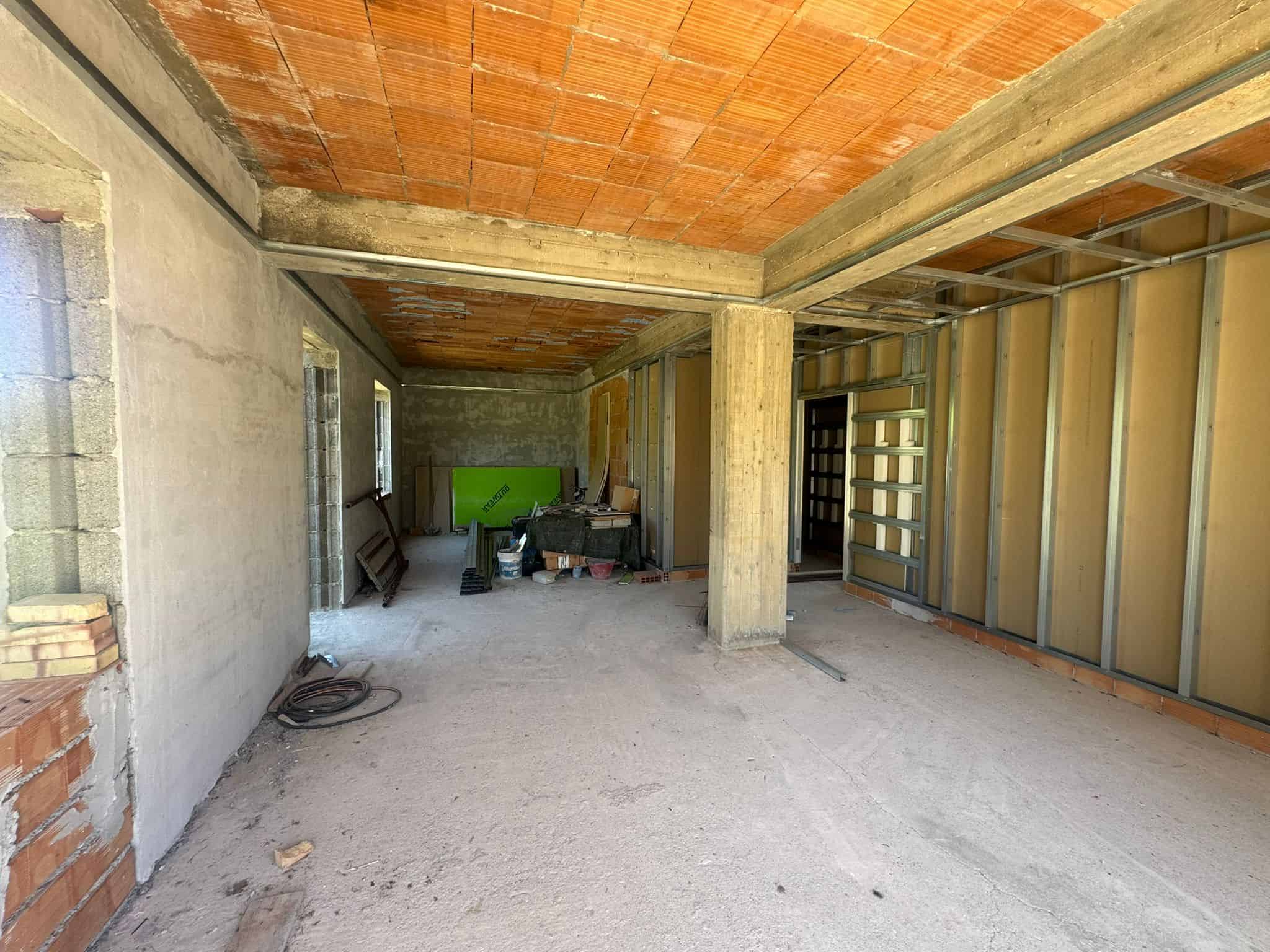 Interno di un edificio in costruzione con pareti in cemento e soffitto in mattoni, pronto per finiture e installazioni.