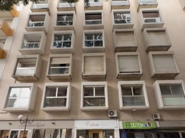 Facciata di un edificio residenziale con balconi e finestre, vista frontale, in un'area urbana, con dettagli architettonici moderni e facciata in tonalità neutre.