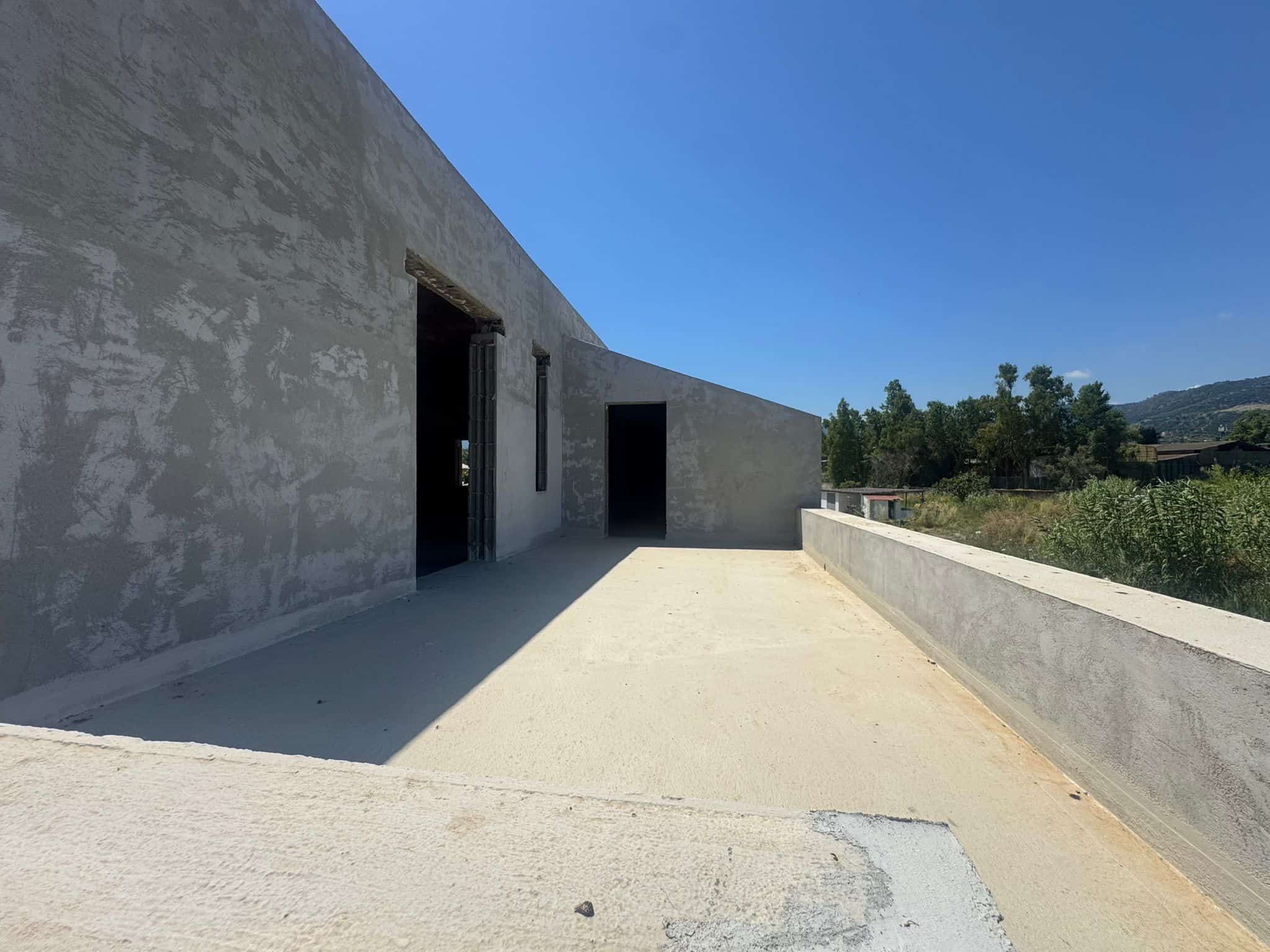 Edificio in costruzione con pareti in cemento e vista panoramica sul paesaggio circostante.