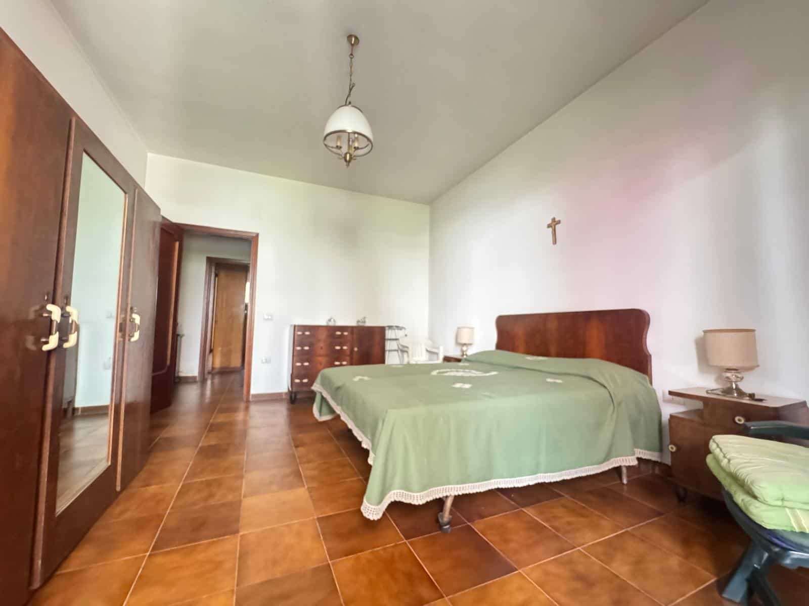 Ampia camera da letto con letto matrimoniale, armadio in legno e comodini, ambiente luminoso e accogliente, ideale per soggiorno confortevole e rilassante.