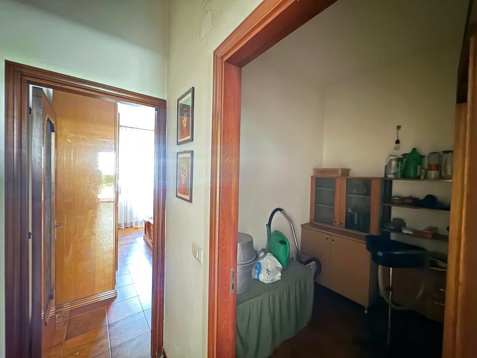 Ampia vista di un ingresso domestico con mobili funzionali, lavatrice e scaffali per la casa, ideale per soluzioni di arredamento pratico e ottimizzazione degli spazi in appartamenti italiani.