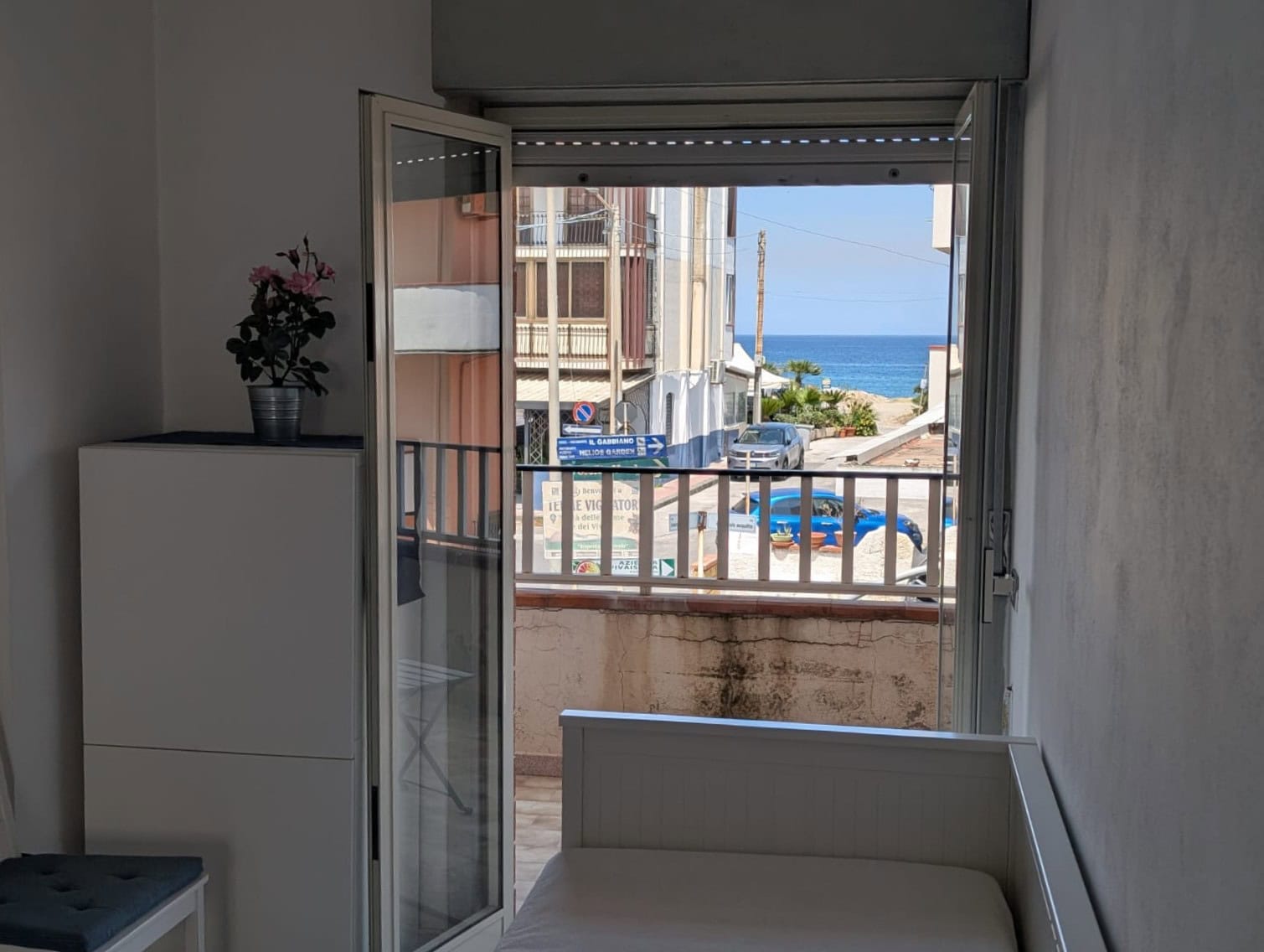 Balcone con vista sul mare e sulla spiaggia, con apertura a portafinestra, in un appartamento vicino alla costa italiana.