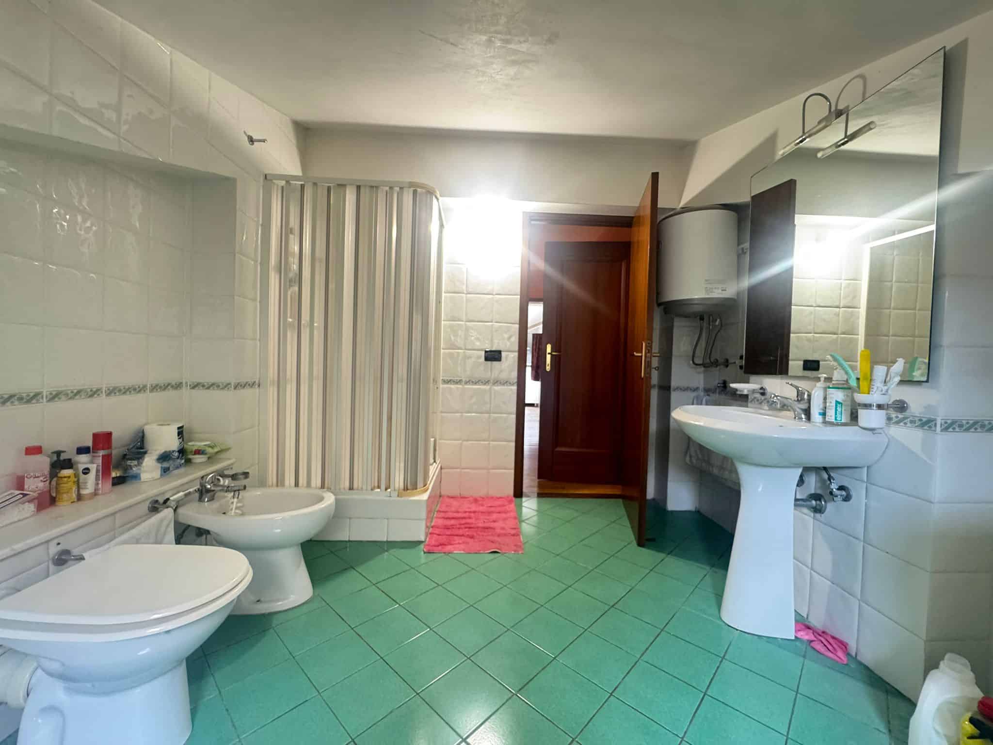 Bagno spazioso con sanitari bianchi, lavabo e specchio, illuminato dalla luce naturale, in una mansarda in vendita a Barcellona P.G.