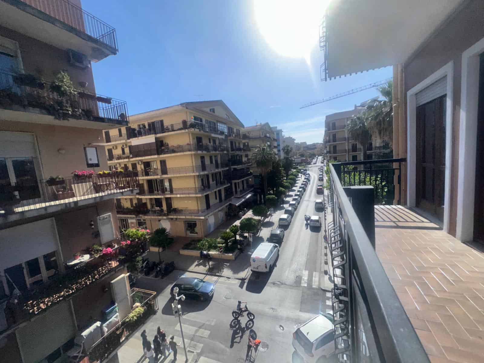 Vista panoramica sulla strada e gli edifici circostanti dall'balcone di un appartamento in città.