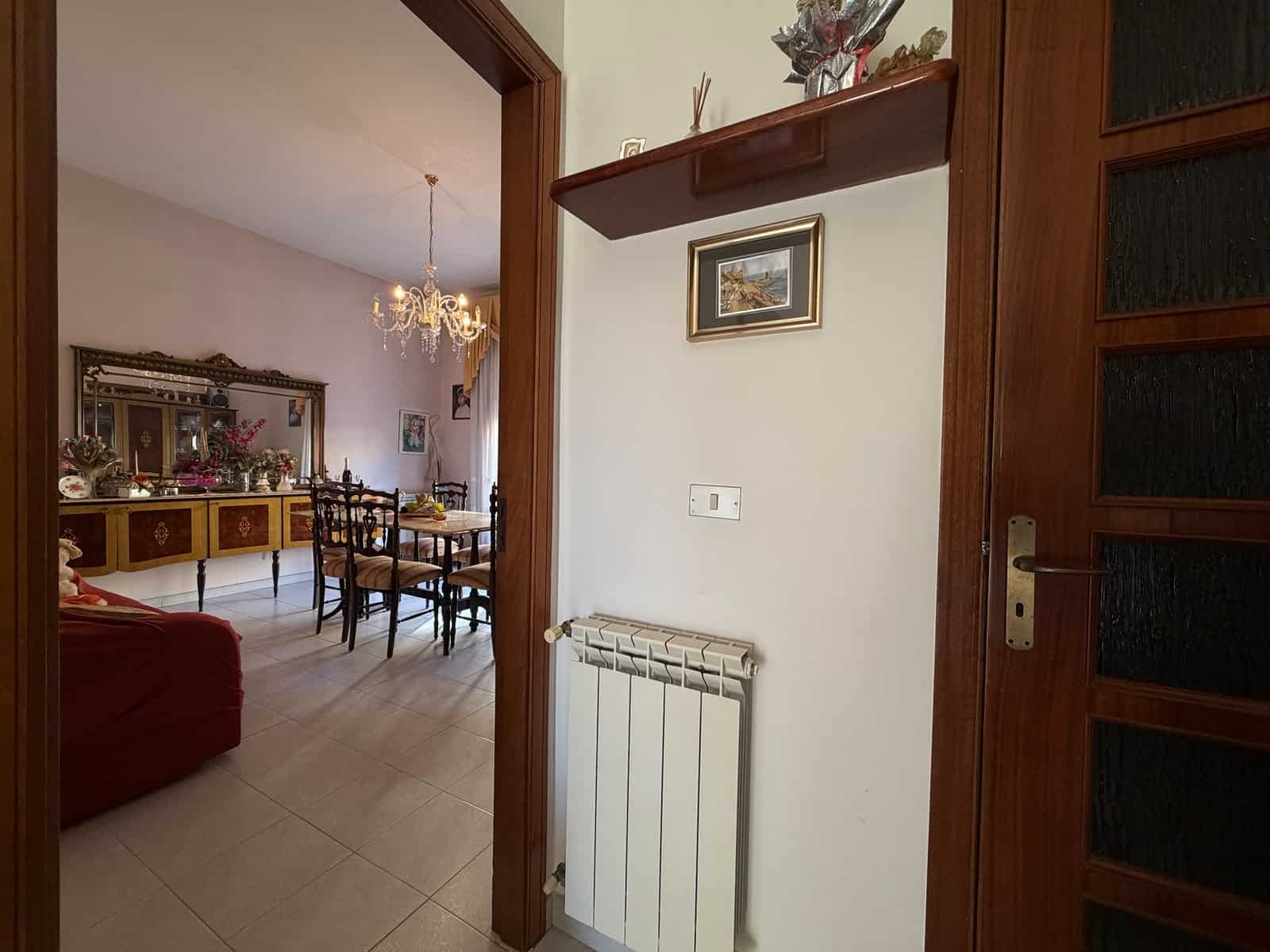 Ingresso dell'appartamento con vista sulla zona giorno, arredato con mobili classici e decorazioni eleganti.