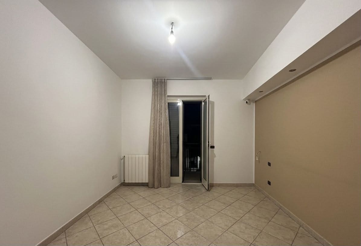 Interno di un appartamento in vendita a Spadafora, con pareti bianche, pavimento in piastrelle e porta finestra che dà su un balcone.
