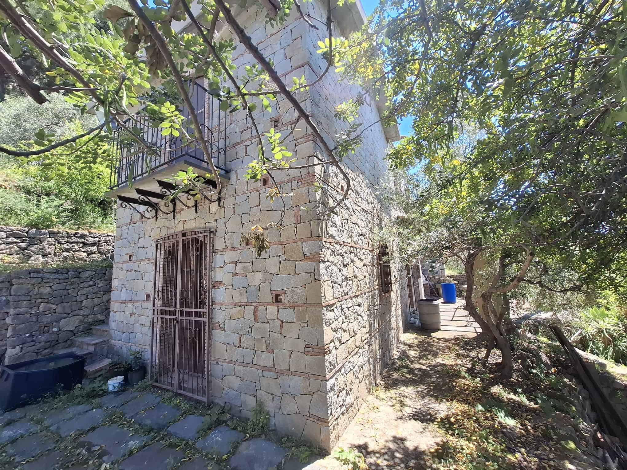 Antico edificio in pietra immerso in un ambiente naturale con alberi e vegetazione, ideale per ristrutturazione e progetti di recupero immobiliare.