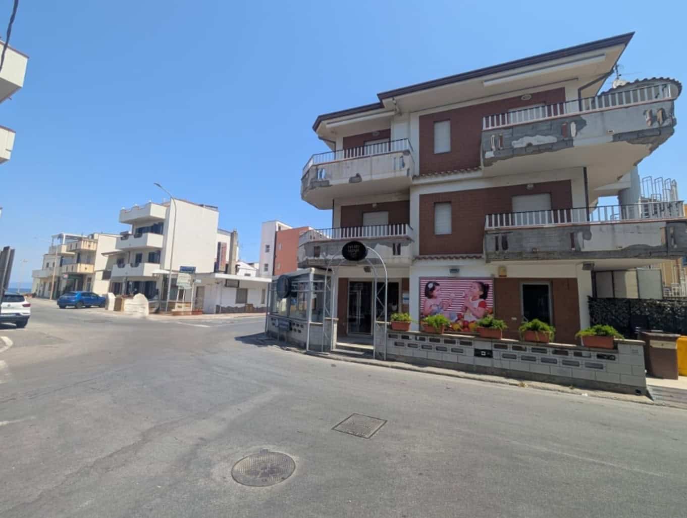 Casa moderna con balconi e negozio al piano terra, zona urbana.