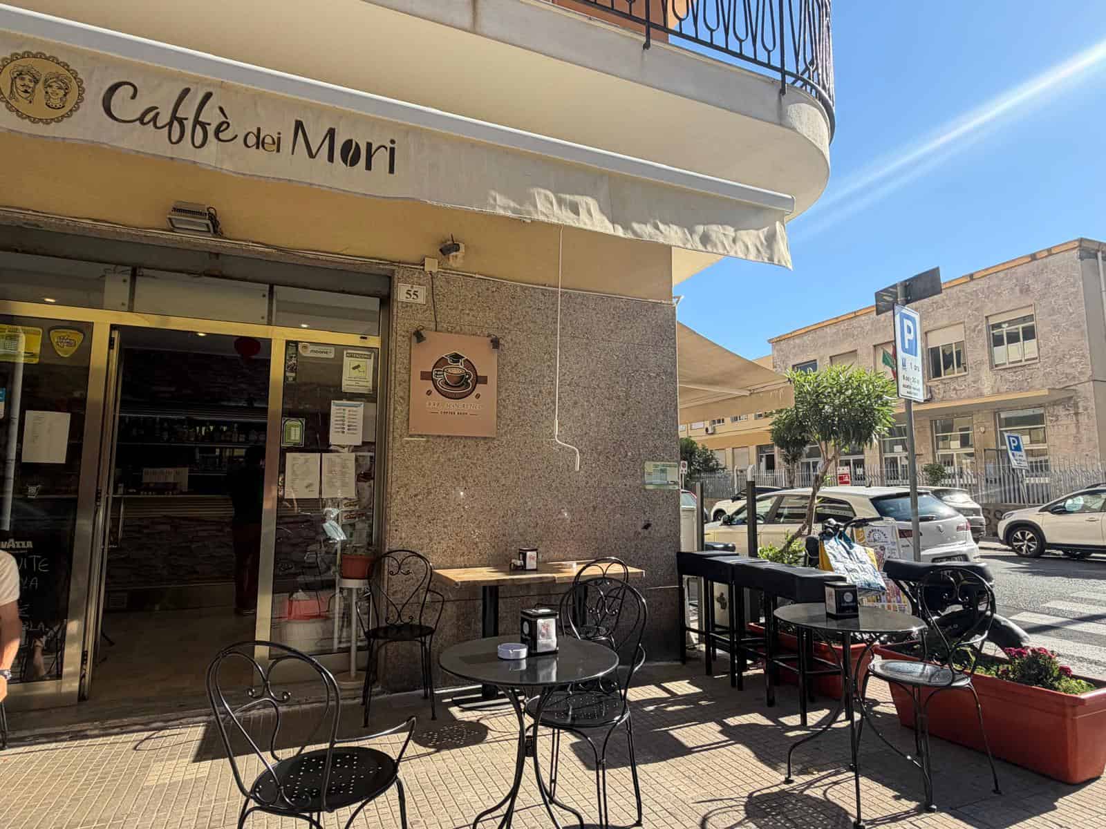 Esterno di un bar con tavoli e sedie all'aperto in Via Risorgimento a Milazzo, Sicilia.