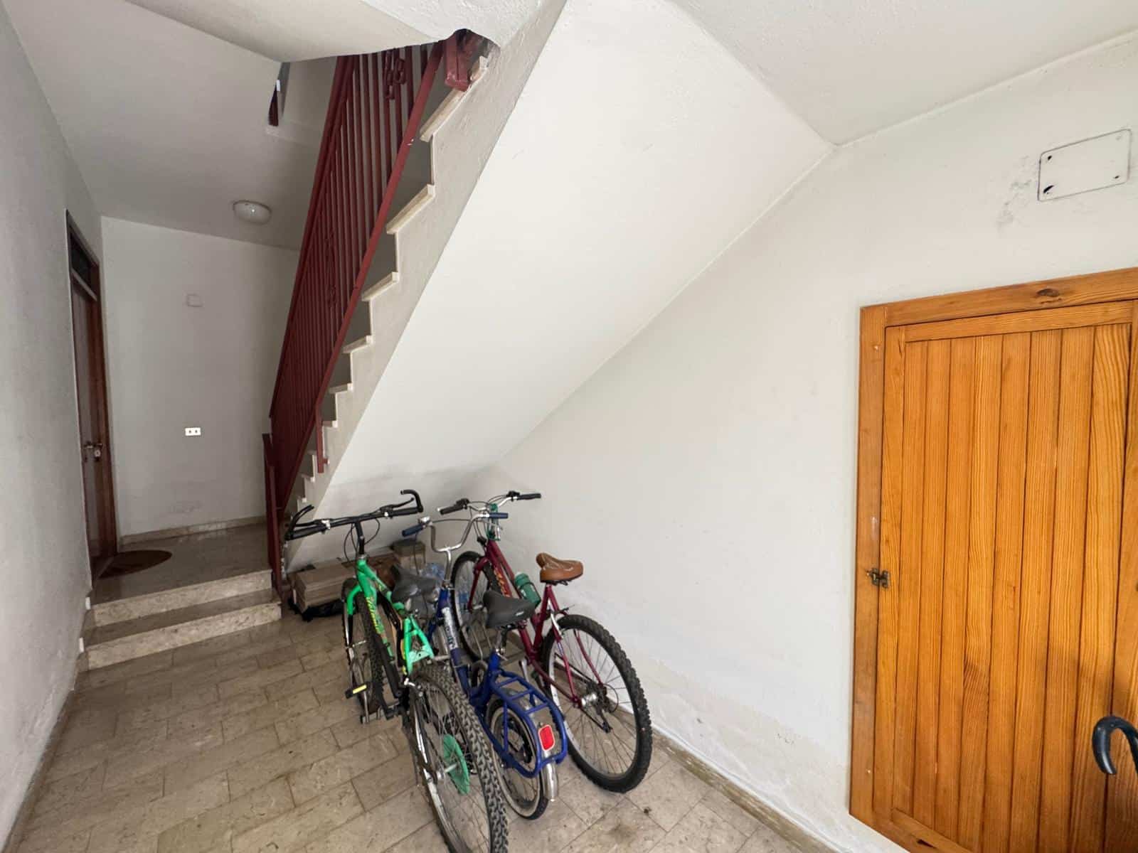 Biciclette da bambino parcheggiate sotto le scale in un ingresso di casa, spazio di stoccaggio per biciclette.
