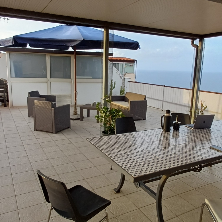 Terrazzo spazioso con tavolo, sedie e vista panoramica sul mare e sulla città, ideale per relax e socializzazione all'aperto.