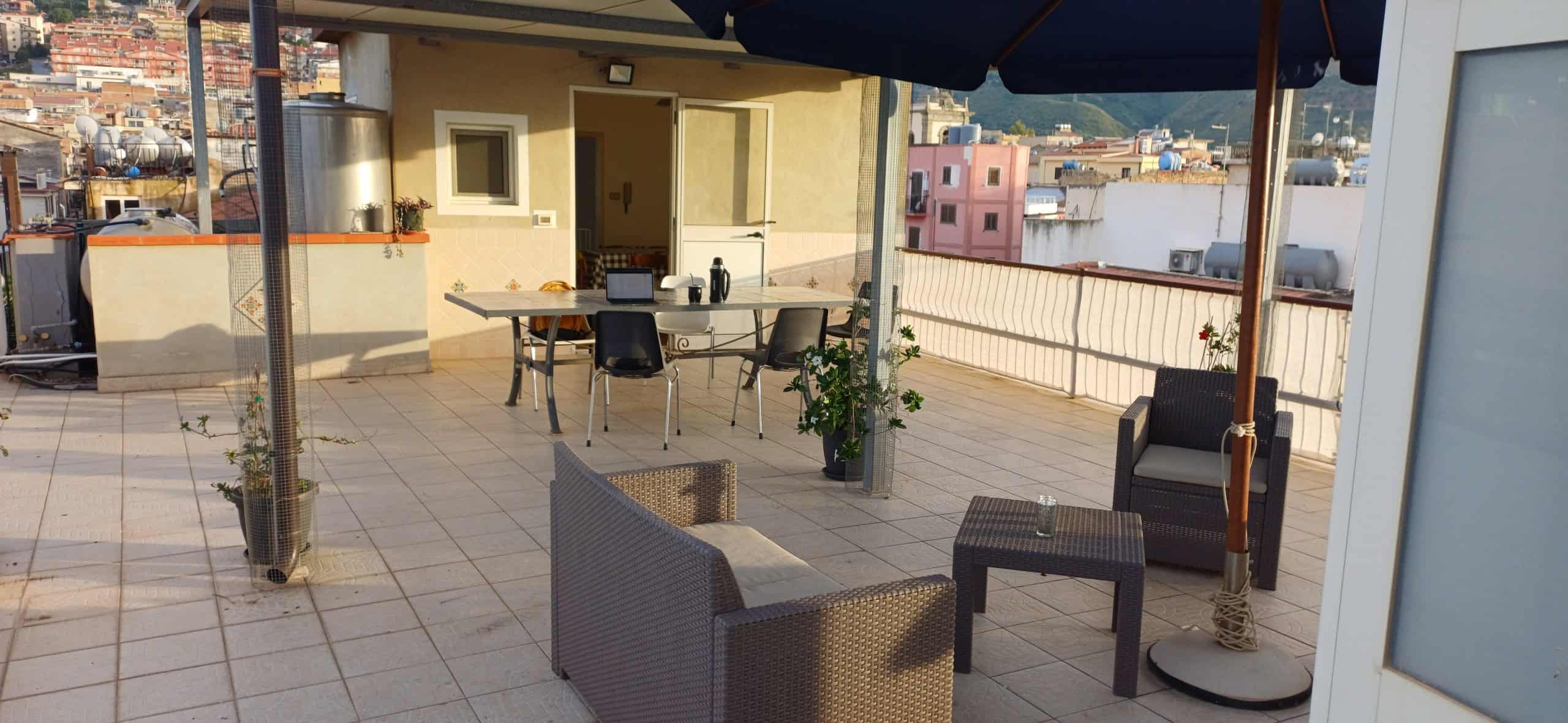 Terrazza spaziosa con mobili da esterno, ombrellone e vista sulla città, ideale per relax e socializzazione all'aperto.
