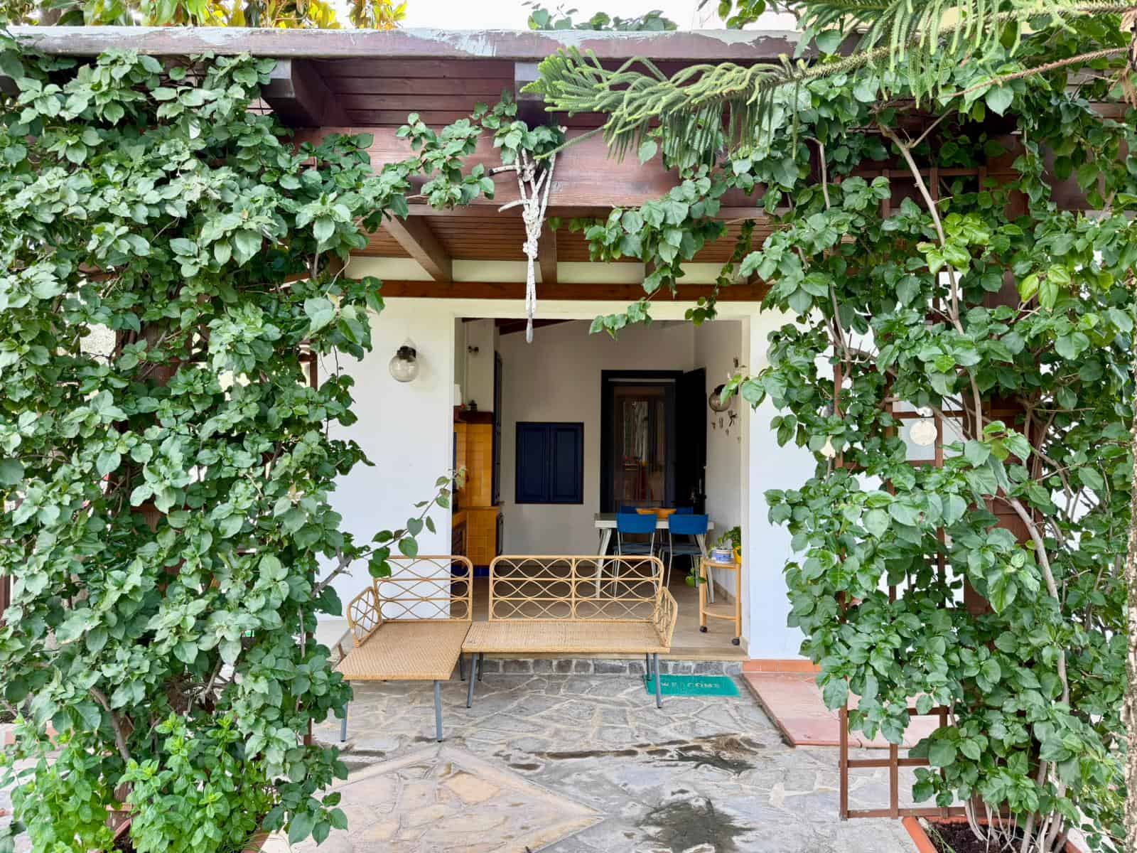 Veranda con mobili da esterno e piante verdi lussureggianti, vista sulla zona relax esterna.