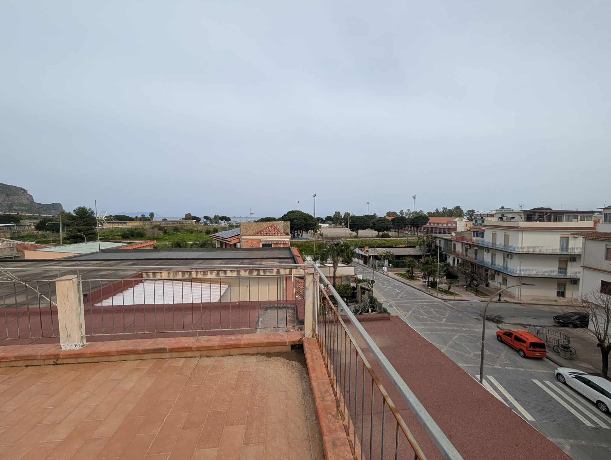 Vista panoramica di un quartiere residenziale con edifici, strade e auto, vista dal terrazzo di un appartamento.