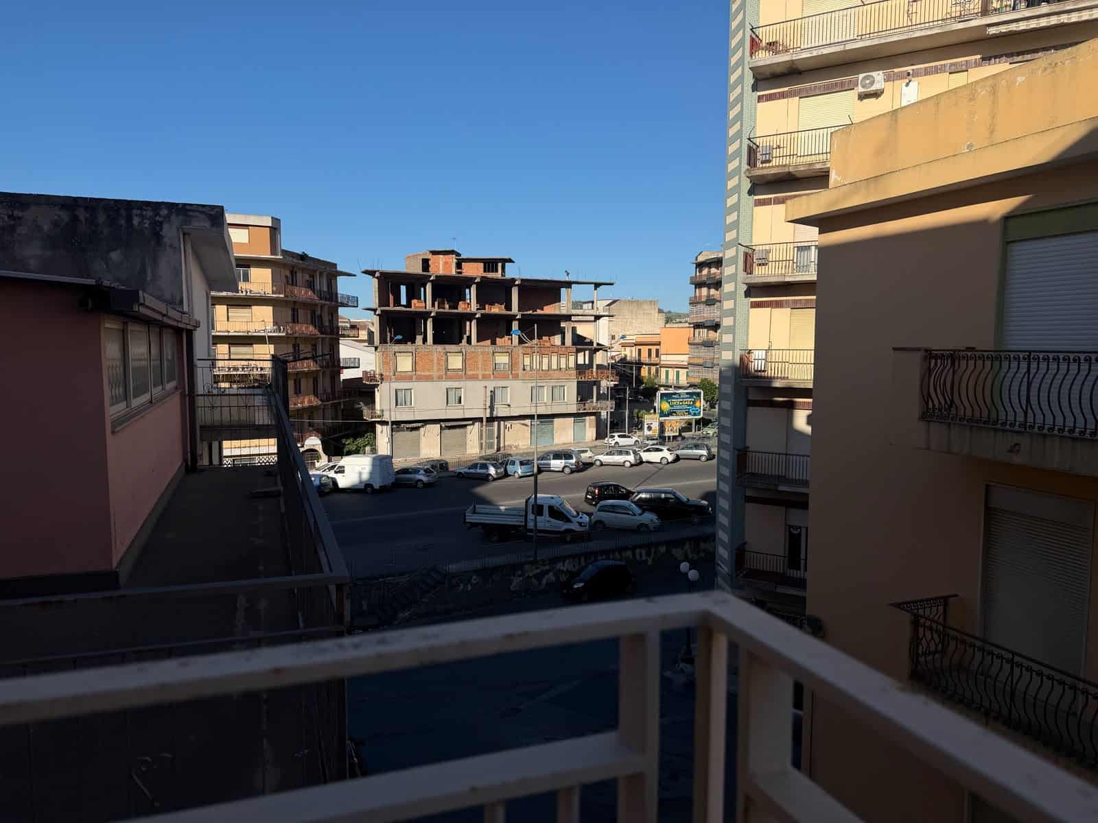 Vista da un balcone di un appartamento a Barcellona P.G., con edifici residenziali e parcheggio sottostante sotto un cielo sereno.