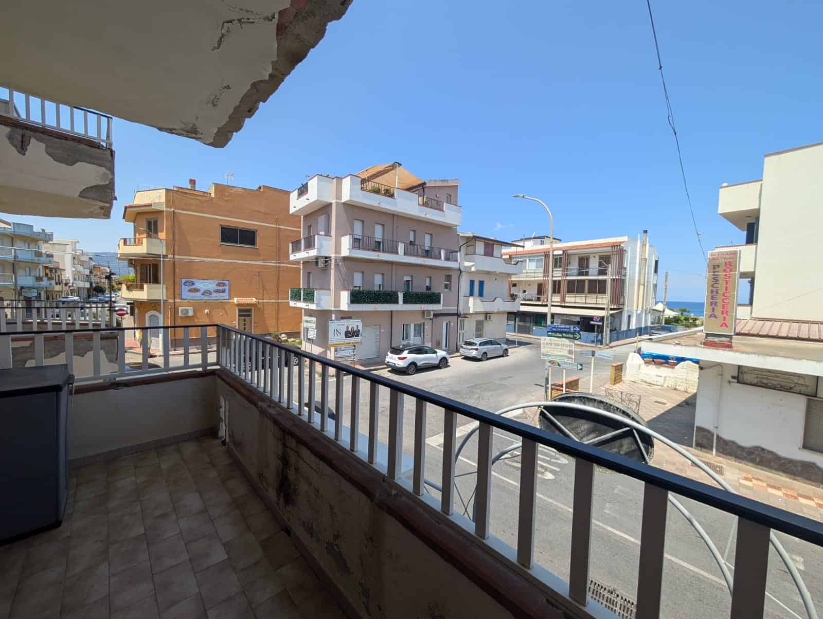 Balcone con vista sulla strada principale e sul mare in lontananza, in un quartiere residenziale di prossimità al mare, ideale per godersi l'aria aperta e il panorama marittimo.