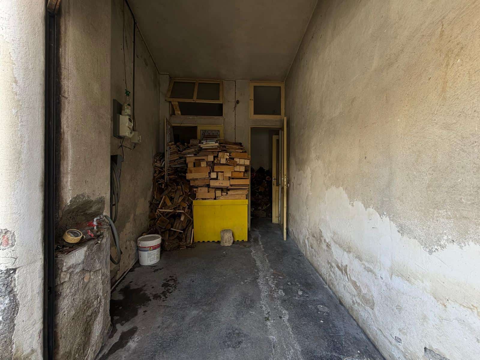 Spazio esterno di una casa in vendita con pareti usurate e materiali di costruzione visibili.