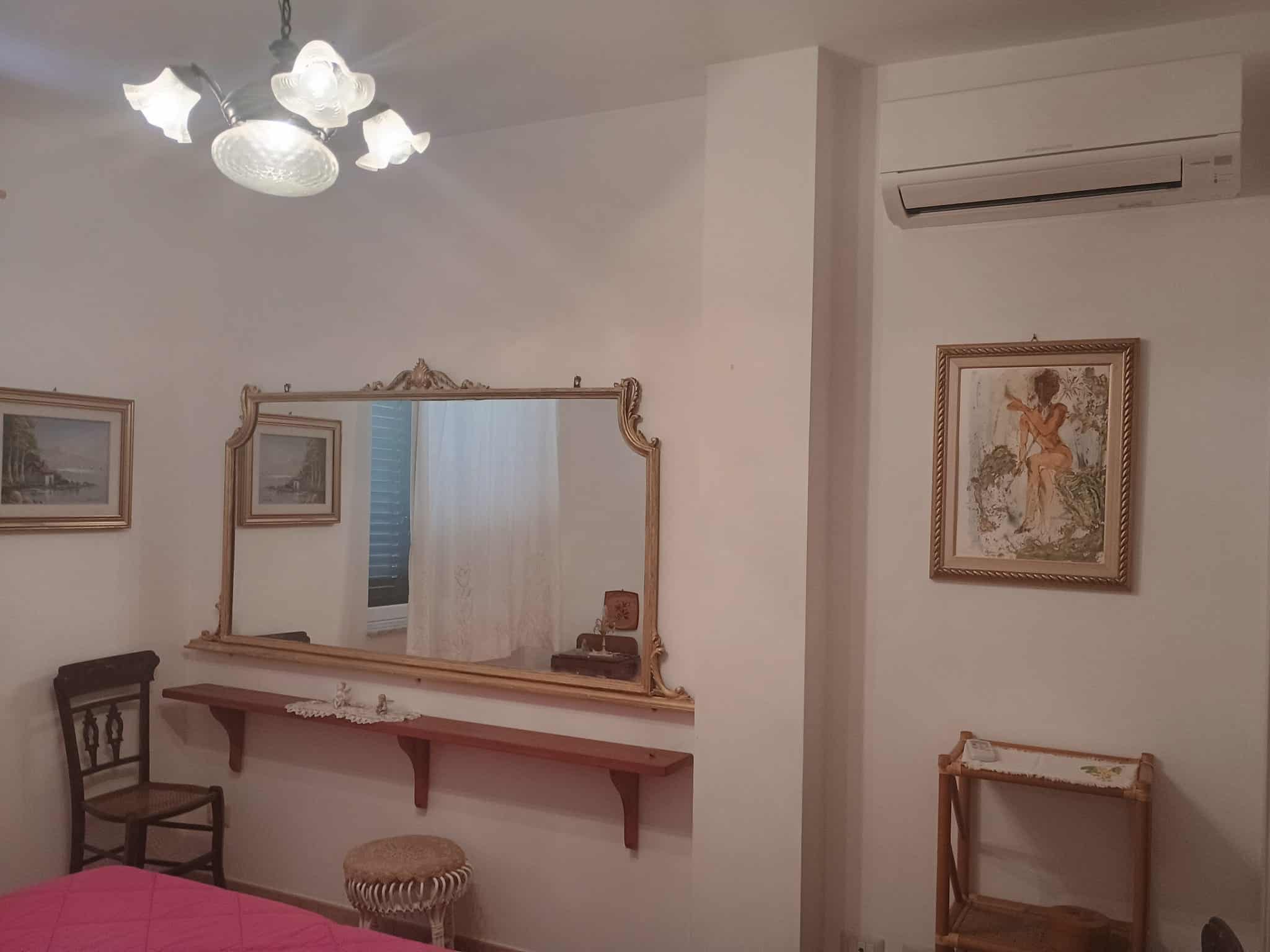 Mobili e decorazioni eleganti in soggiorno classico con grande specchio, quadro artistico e aria condizionata.