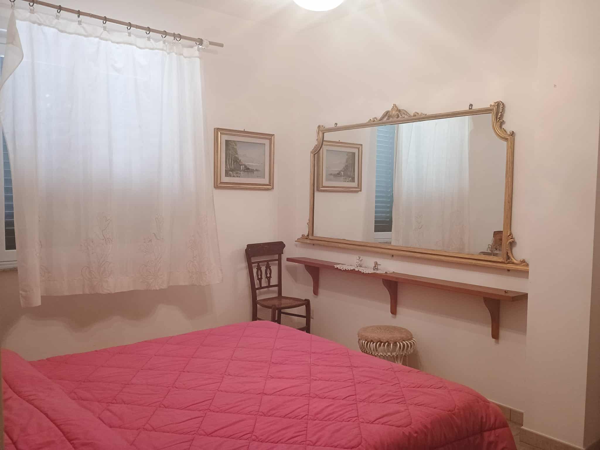 Camera da letto con letto matrimoniale, grande specchio antico e decorazioni classiche, ambiente luminoso e accogliente, ideale per residenze di charme.