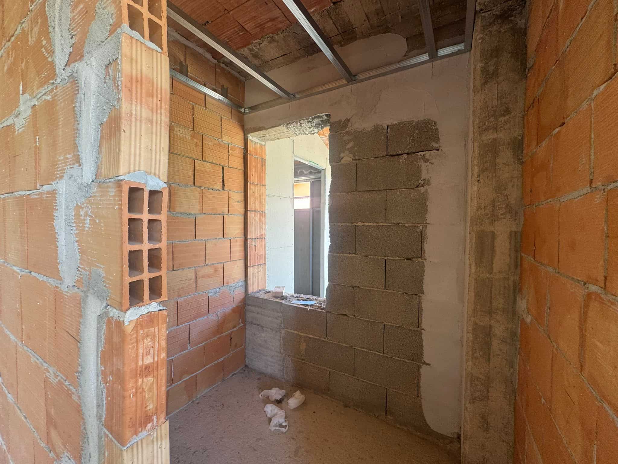 Interno di un edificio in costruzione con pareti in mattoni e cemento, pronto per finiture.