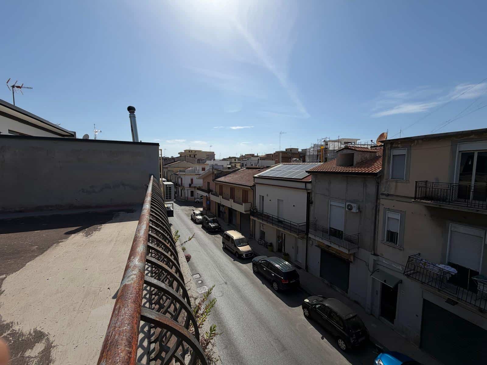 Vista di un quartiere residenziale a Barcellona P.G. con case e auto parcheggiate lungo la strada sotto un cielo sereno.