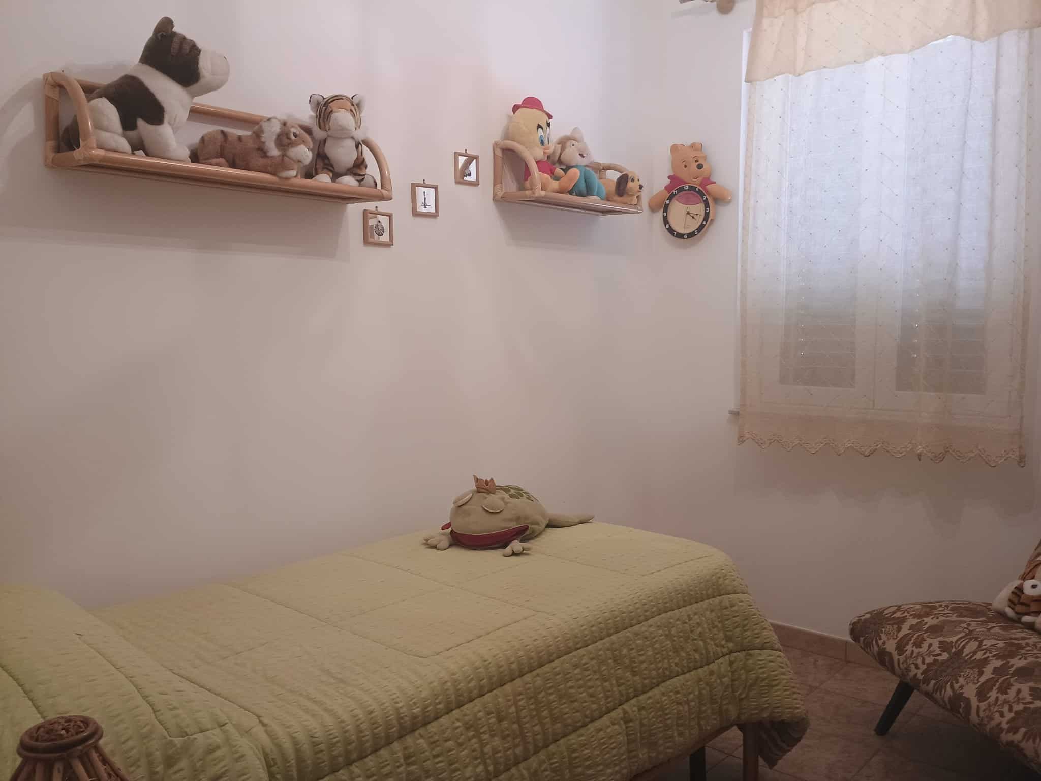 Letto per bambini con peluche e decorazioni, ambiente luminoso e accogliente, ideale per cameretta di bambino.