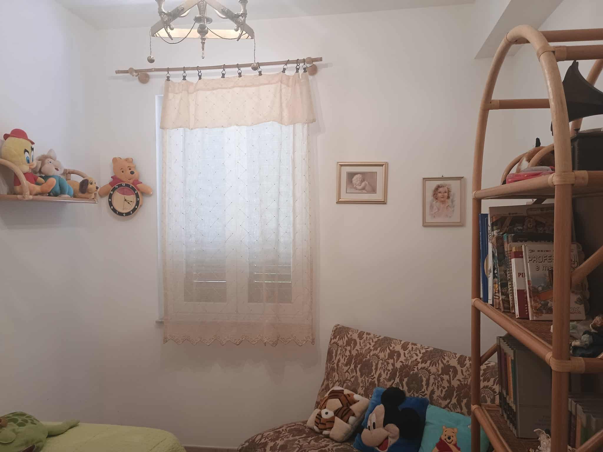 Cameretta per bambini con libreria, decorazioni e giochi, ambiente accogliente e luminoso, ideale per il relax e lo studio dei più piccoli.