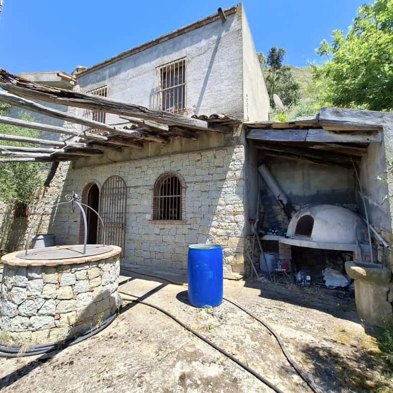 Pannello solare e forno a legna in cortile esterno di una casa rurale in pietra, con ambiente naturale e vegetazione circostante, in Italia.
