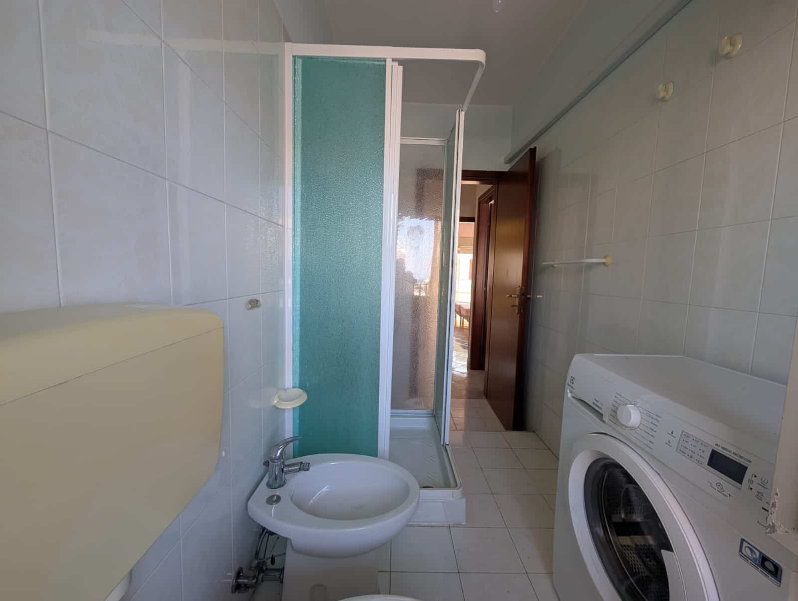 Bagno con doccia, lavatrice e bidet in spazio ottimizzato.