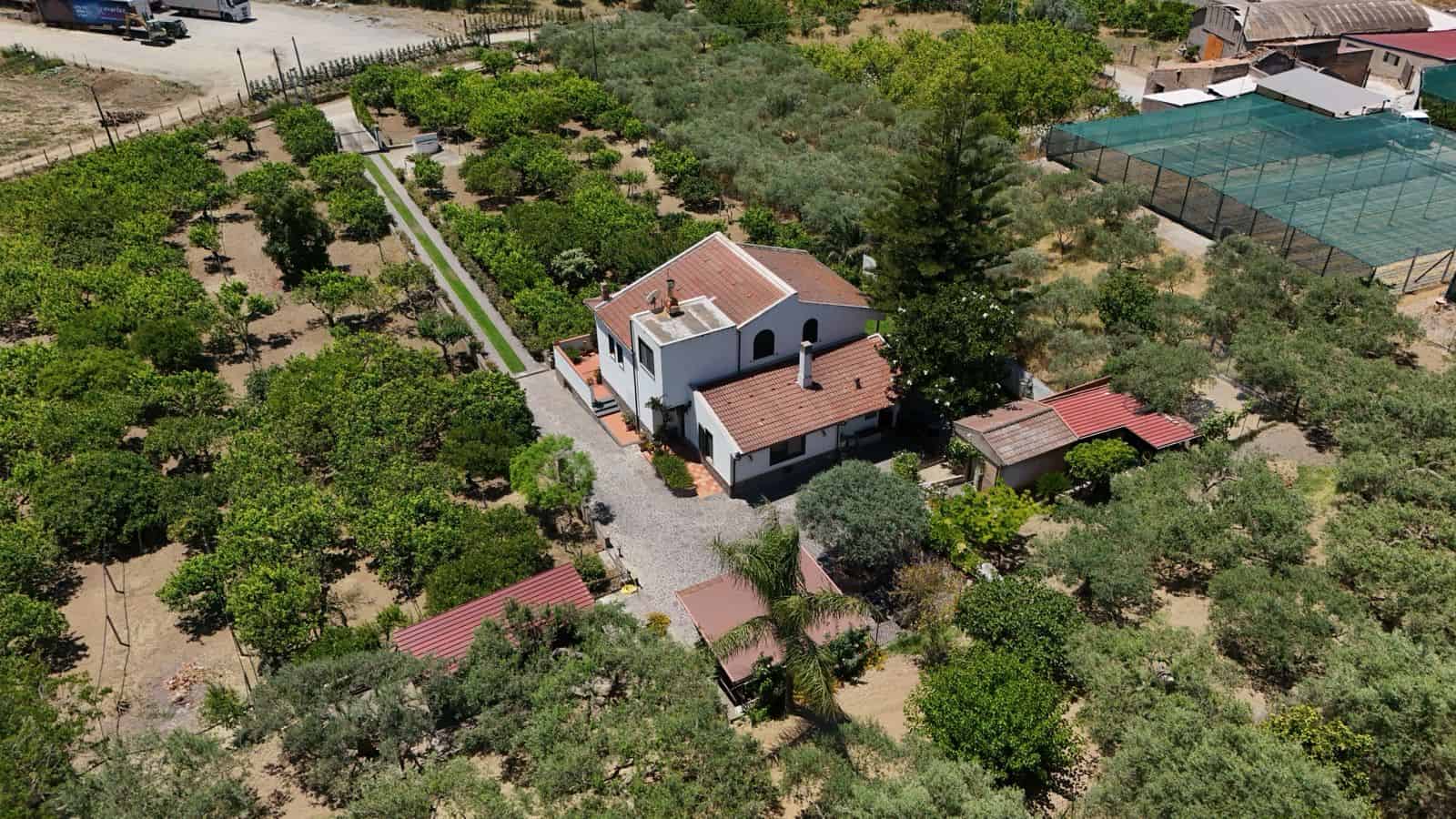 Villa singola in vendita a Terme Vigliatore circondata da giardini e alberi, con ampio spazio esterno e accesso privato.