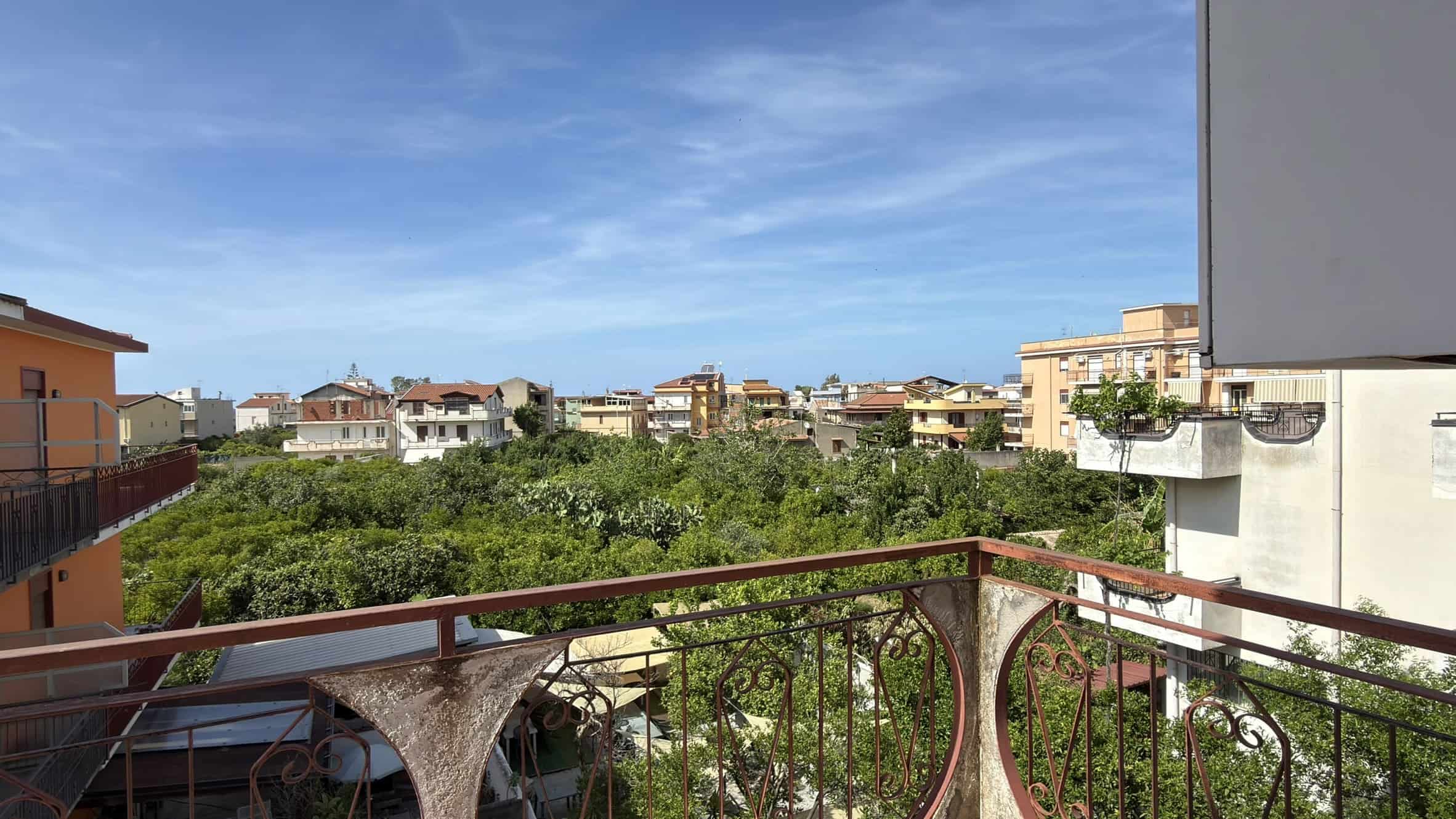 Vista panoramica di un quartiere residenziale con edifici moderni e un ampio spazio verde sotto un cielo sereno.