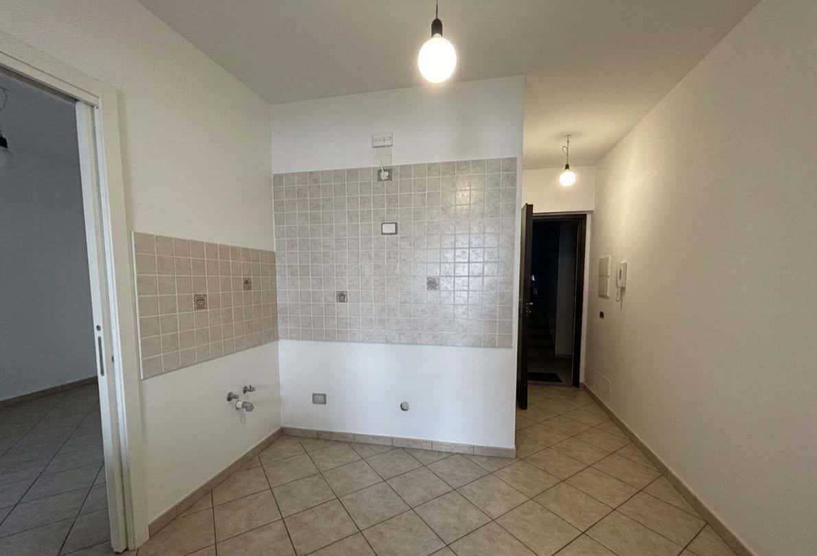 Interno di un appartamento in vendita con pareti bianche, piastrelle beige e illuminazione semplice.