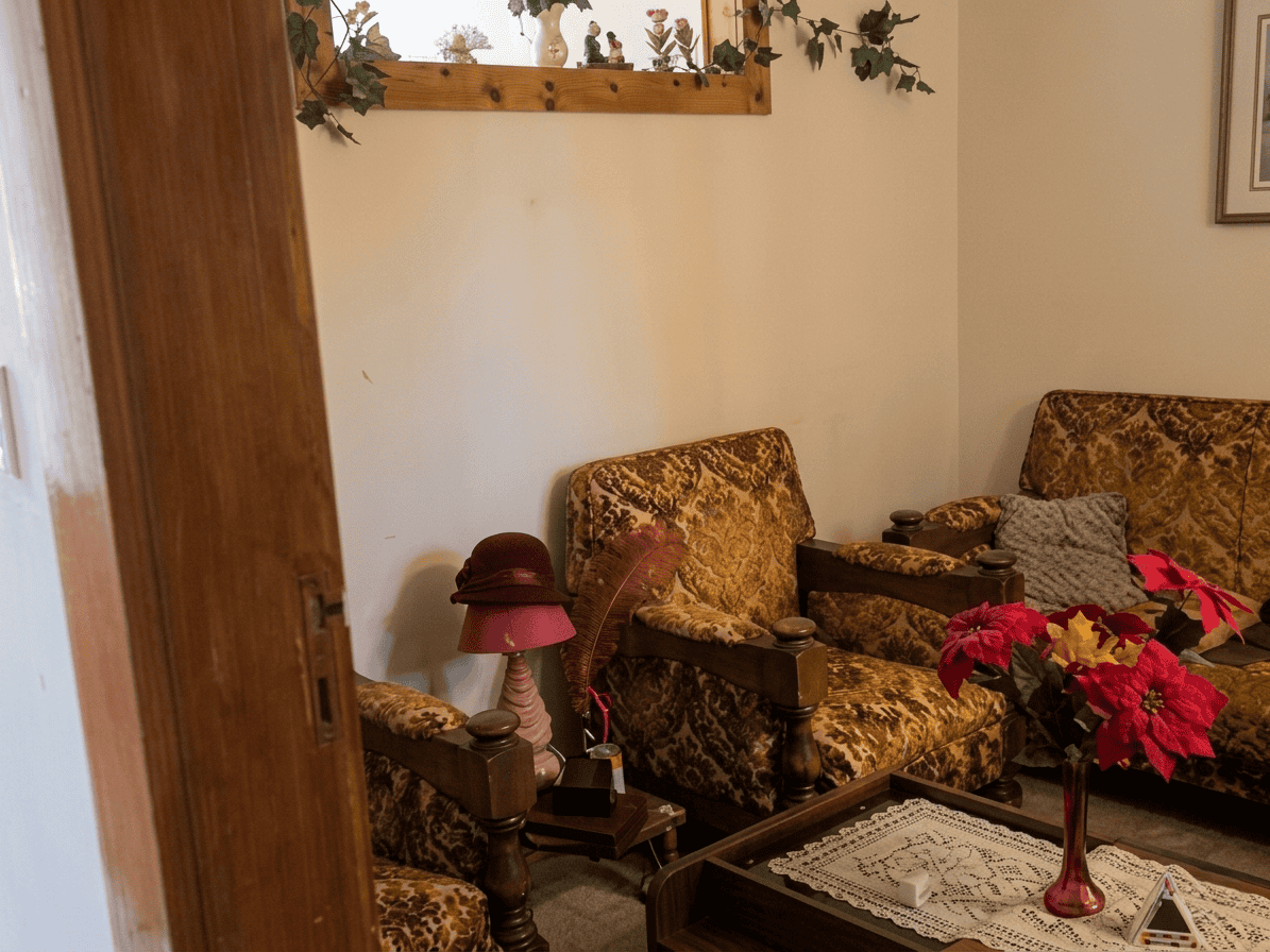 Salotto accogliente con poltrone in tessuto damascato, tavolino e decorazioni floreali, ambiente caldo e invitante.