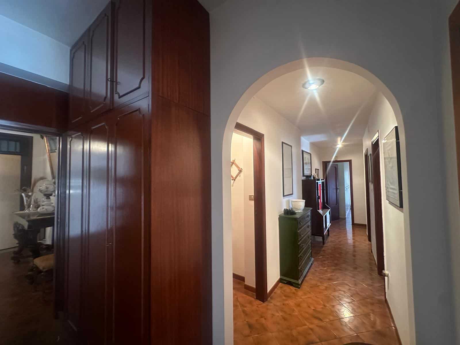 Elegante corridoio interno di casa con pavimento in parquet, pareti bianche e arredi moderni, ideale per residenze di alta qualità e comfort abitativo.