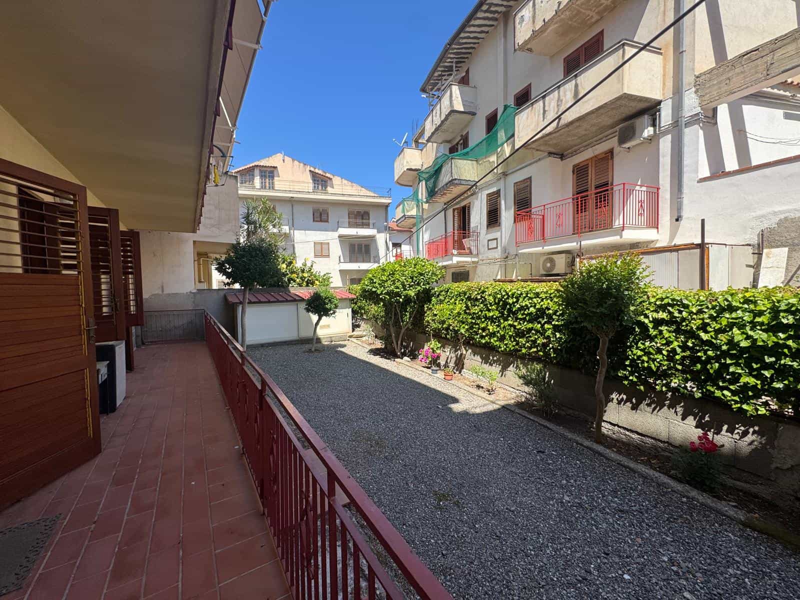 Cortile condominiale con piante e balconi di appartamenti in un complesso residenziale a NextCasa, Italia.