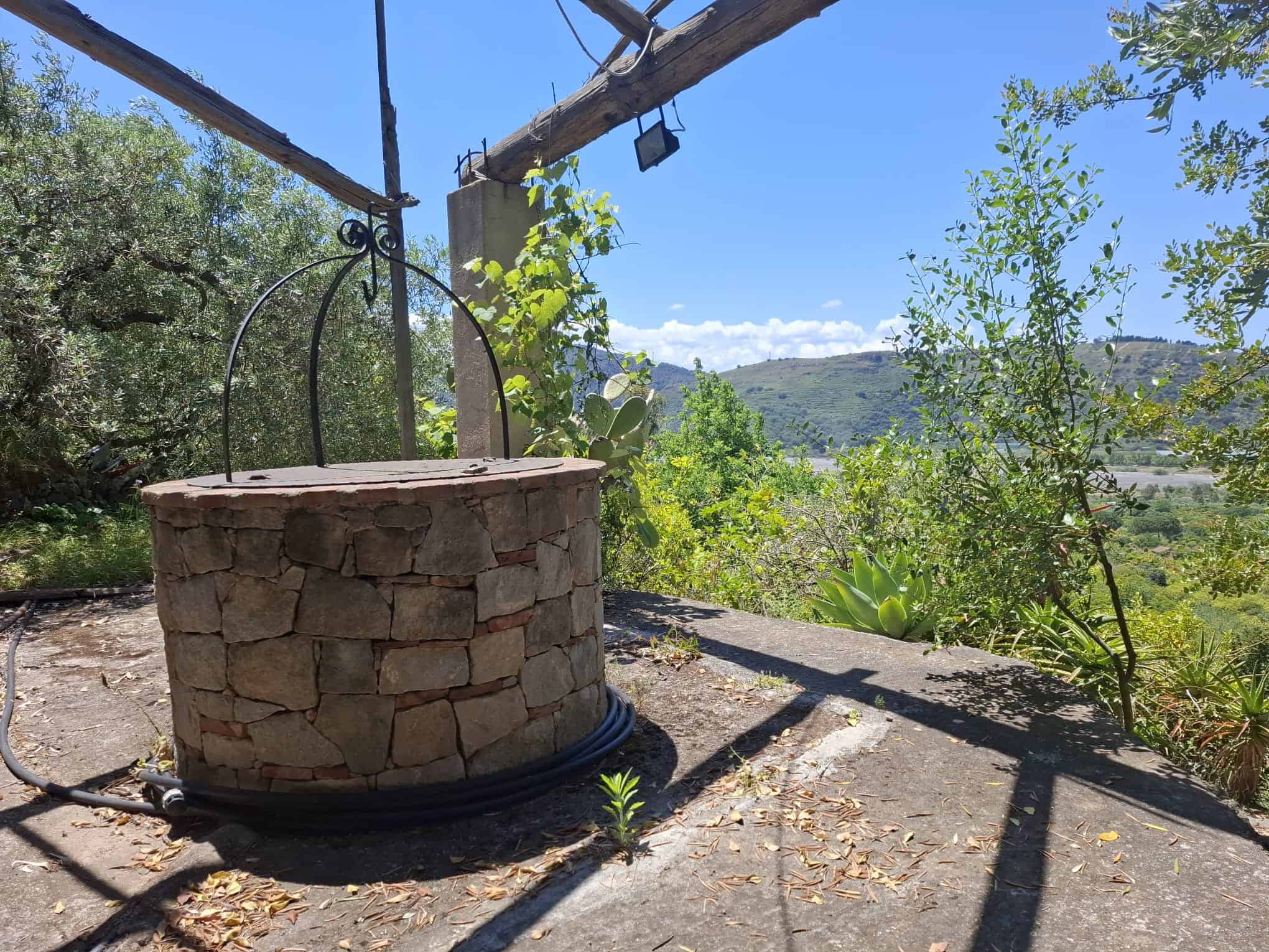 Antico mulino in pietra con vista panoramica sulla campagna toscana, ideale per relax e natura, immerso nel verde con cielo azzurro e paesaggi collinari.