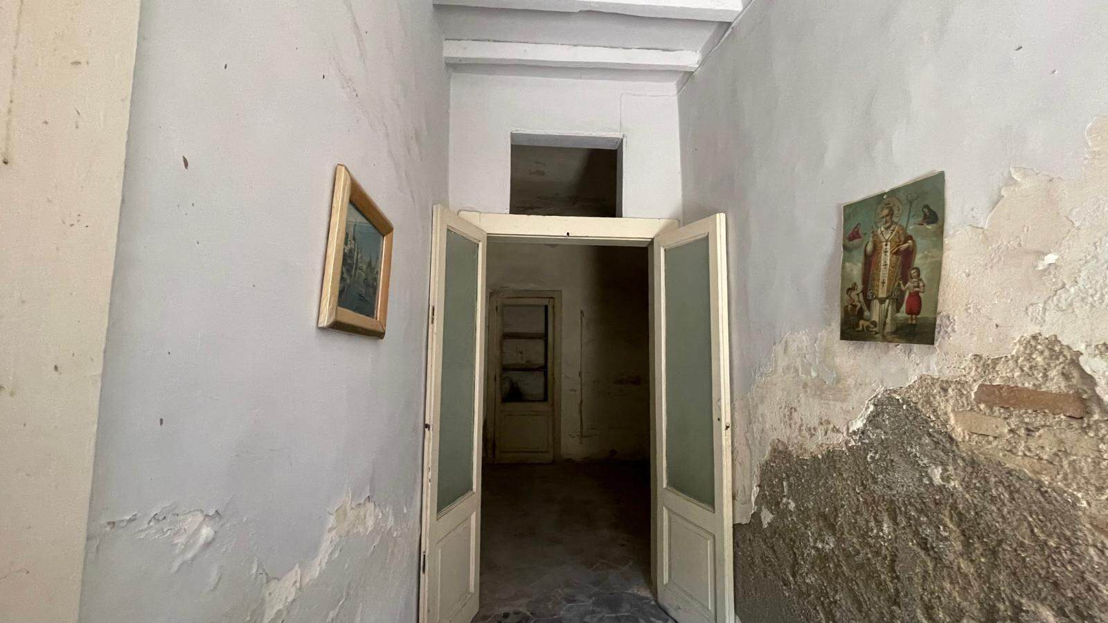 Porta d'ingresso in stile vintage con pareti deteriorate e dipinti artistici alle pareti.
