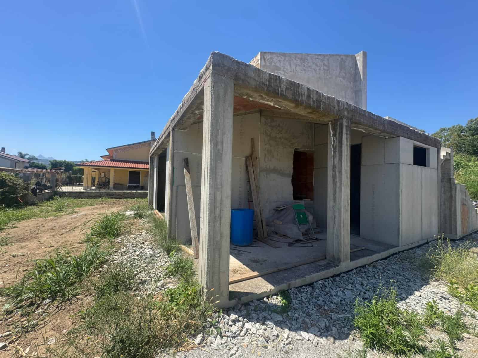 Struttura in costruzione di una casa con pareti in cemento e supporti in calcestruzzo, in fase di sviluppo.