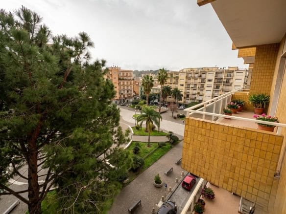 Vista panoramica di un quartiere residenziale con alberi, edifici e balconi fioriti, vista da un appartamento in un condominio urbano.