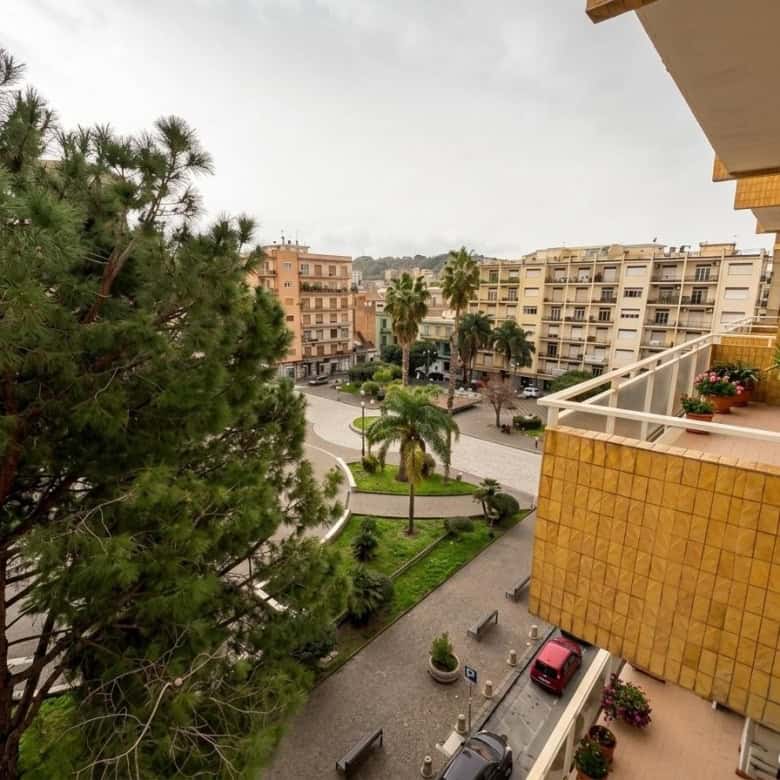 Vista panoramica di un quartiere residenziale con alberi, edifici e balconi fioriti, vista da un appartamento in un condominio urbano.