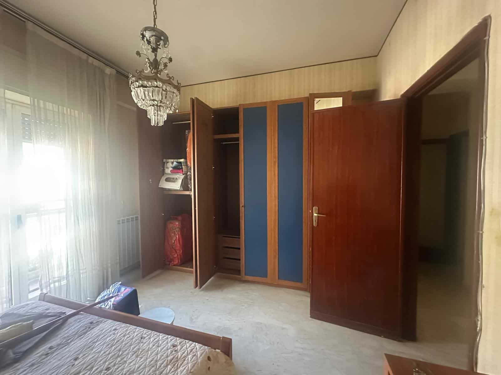 Armadio a muro in camera da letto con ante in legno e dettagli blu, ideale per ottimizzare lo spazio e organizzare gli abiti.