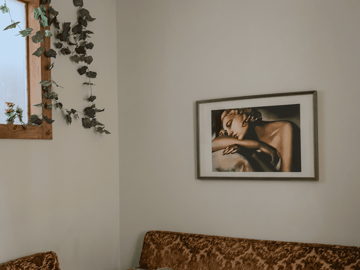 Immagine di un quadro decorativo con donna addormentata appeso alla parete di un soggiorno moderno.