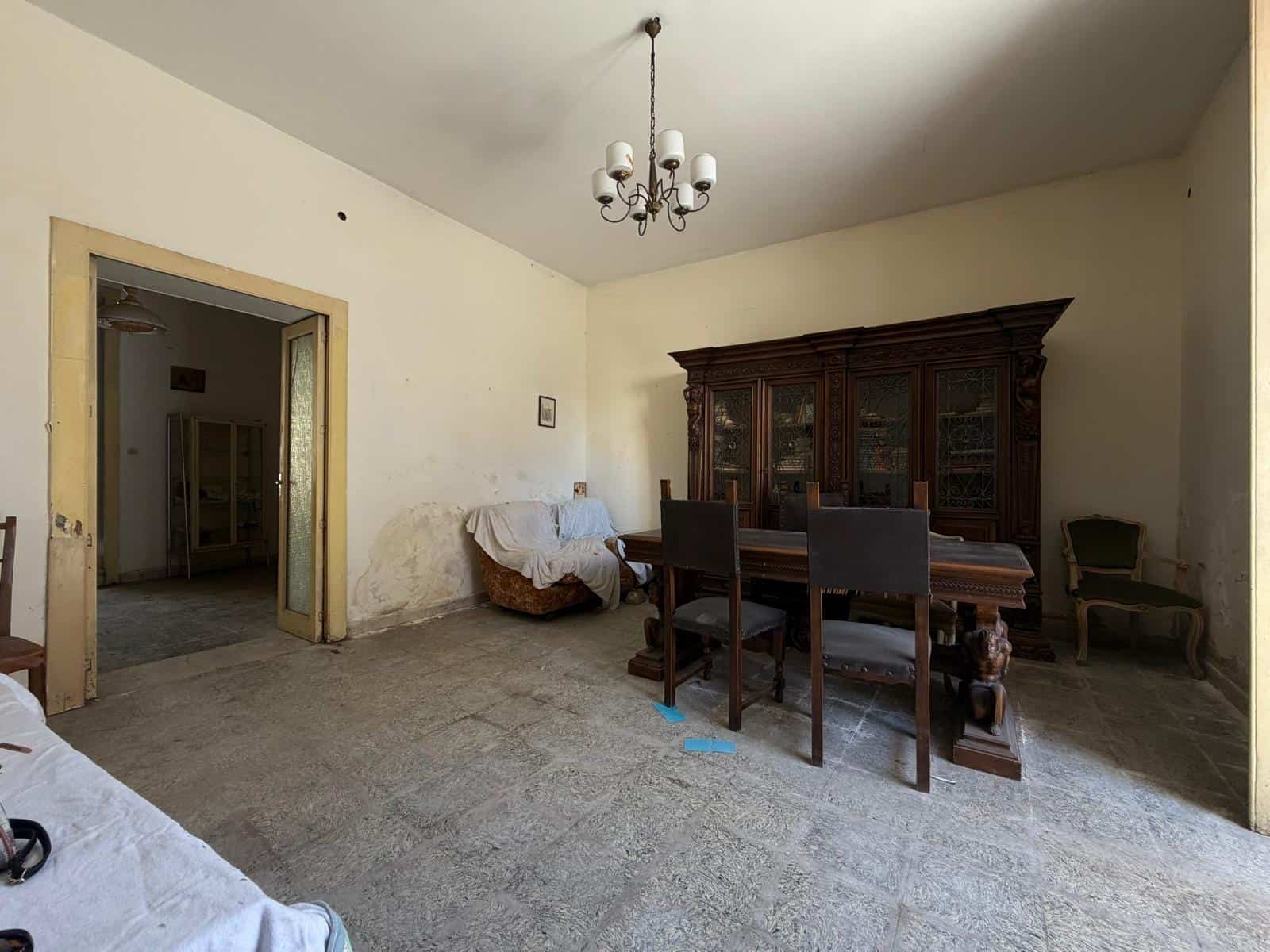 Interno di una casa indipendente con pareti bianche, mobili in legno e un lampadario centrale.
