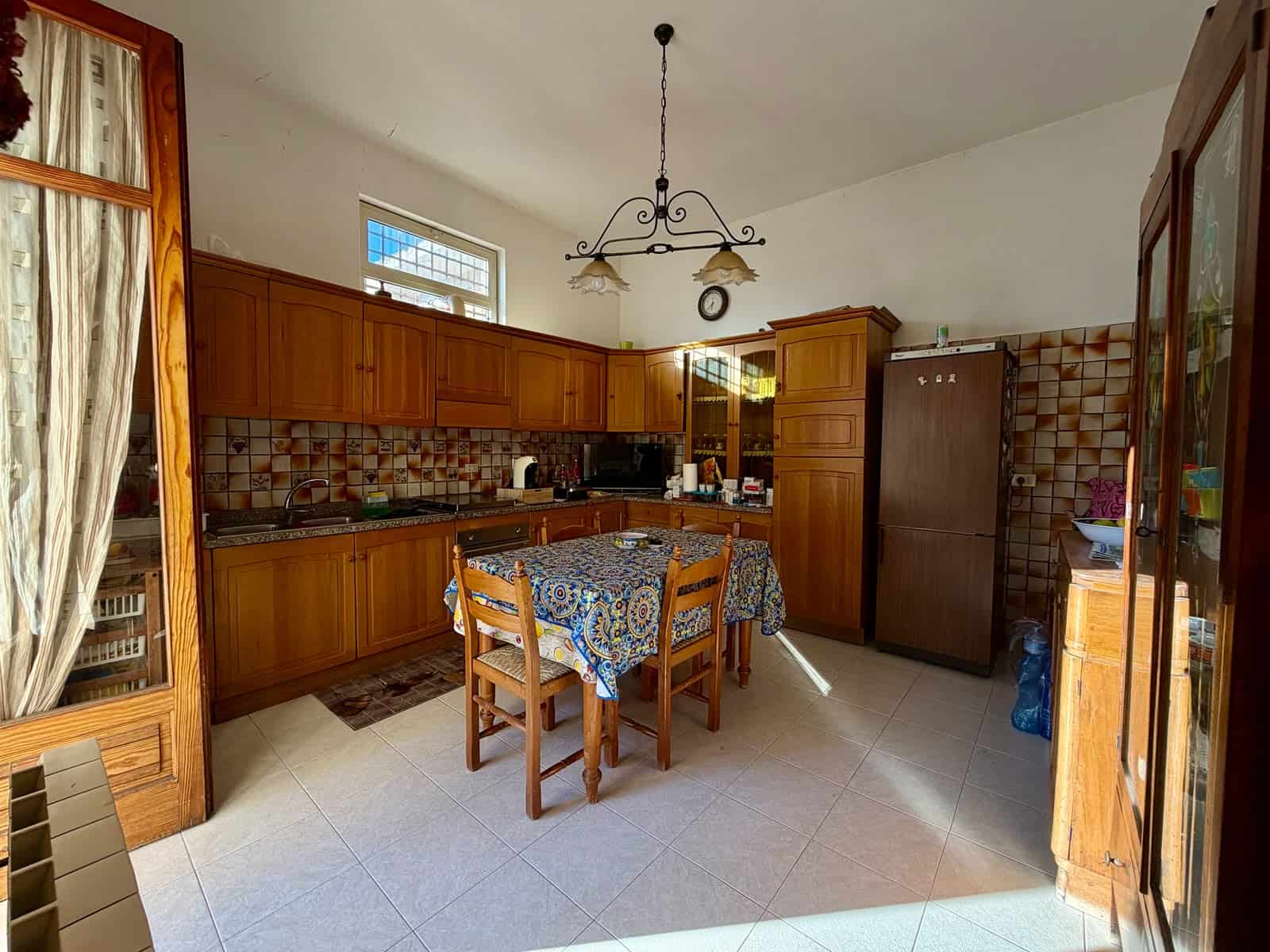 Cucina spaziosa con mobili in legno, tavolo centrale e frigorifero in un appartamento in vendita a Barcellona P.G.